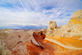 Swirling vortex-like sandstone patterns of white and orange rock at White Pocket, wispy cirrus clouds streaking overhead