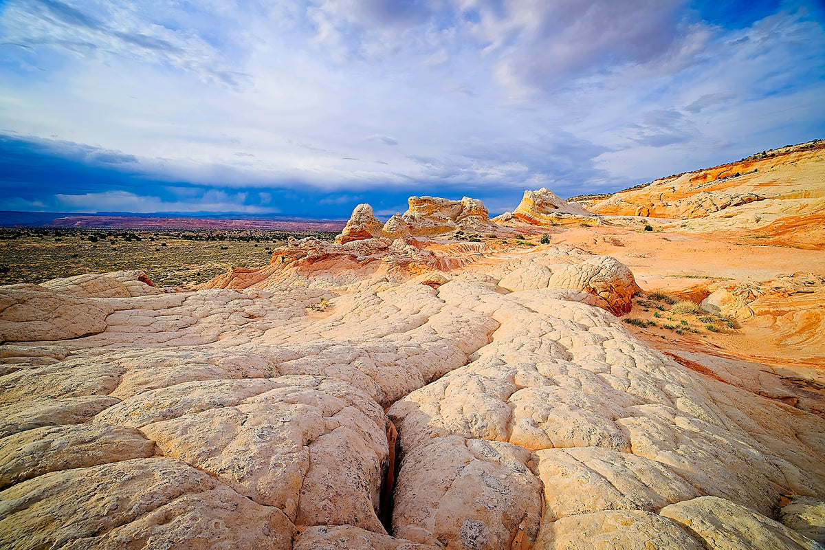 An ivory-white sandstone dome rising like a bastion above orange rock terraces, wide desert view under a moody sky