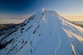 An aerial view of Mount Hood's snow-covered summit at first light, a sea of clouds filling the valley far below
