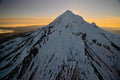 The sun breaking over Mount Hood's summit ridge in silhouette, amber light spreading along the horizon at sunrise
